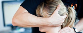 Therapeut führt Übung am Nacken eines Patienten durch