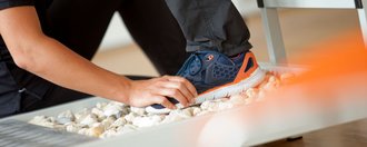 Patient läuft über Steinmatte während Therapeutin den Fuß hält