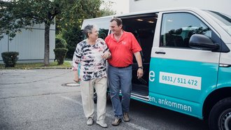 Fahrer des f+p VW-Bus geleitet ältere Frau zum Zielgebäude