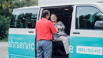 Fahrer hilft fröhlicher älterer Frau in den f+p Bus